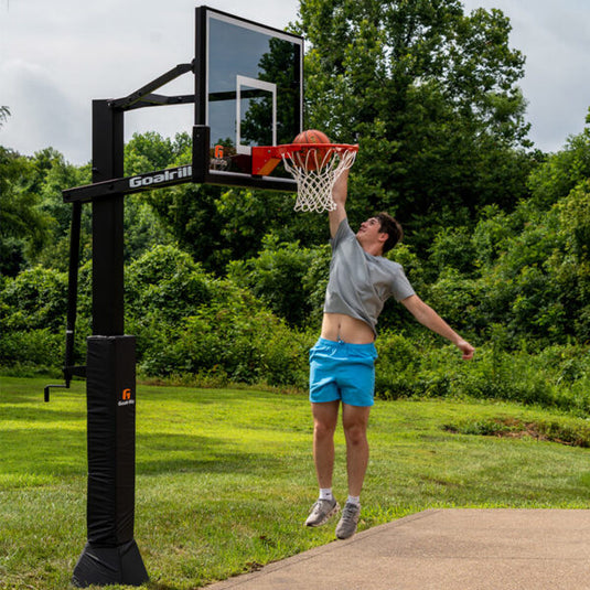 Person playing basketball with a Goalrilla basketball hoop in a park setting.